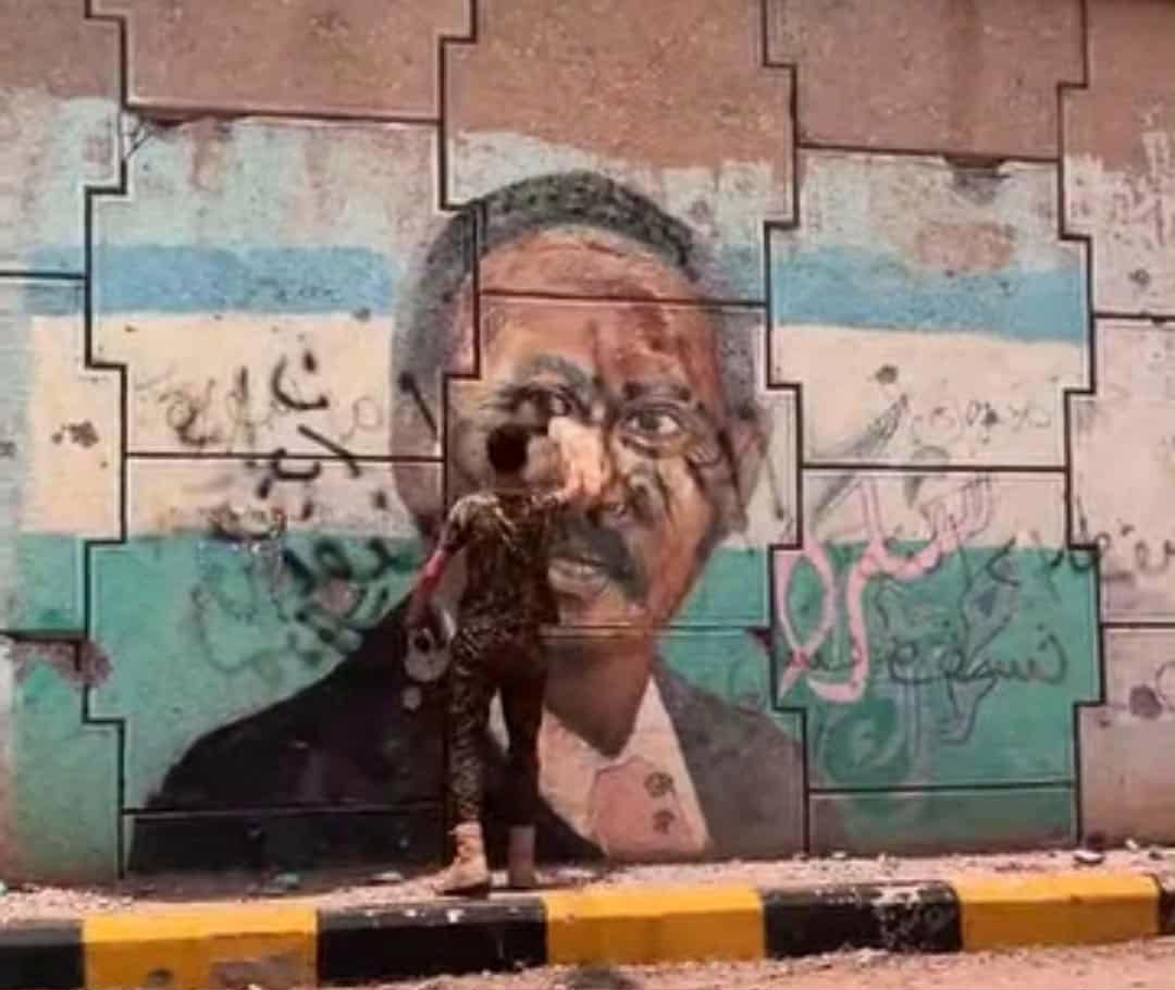 «غضب “القحاتة” يتصاعد» شاب سوداني يشعل التوتر بصورة “حمدوك” على جدار في الخرطوم